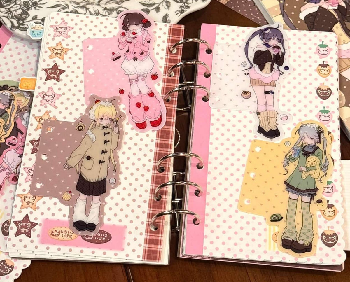 Illustrated character planner dividers displayed in an open ring binder with pink, yellow, and pastel decorative details.