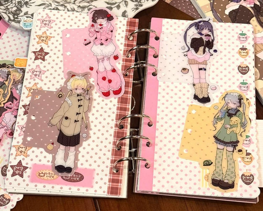 Illustrated character planner dividers displayed in an open ring binder with pink, yellow, and pastel decorative details.